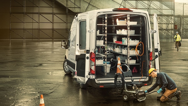 Ford Transit van  blanca de servicio con interior  organizado y trabajador en la parte  trasera.